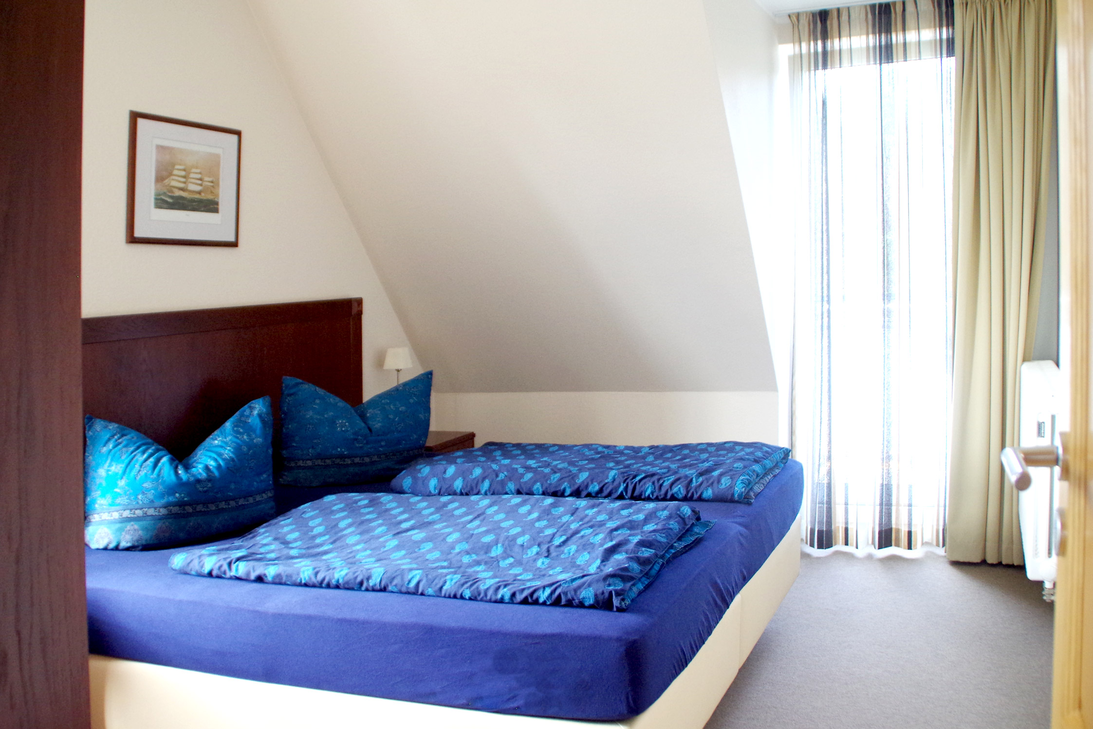 Das Foto zeigt ein großes gemütliches Doppelbett in einem der vielen Schlafzimmer des Bine Ferienhauses direkt an der SOtsee.