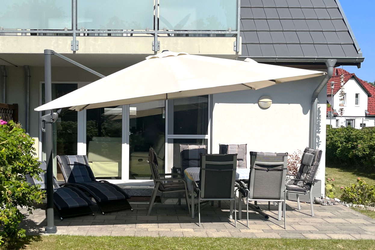 Auf dem Bild sieht man die Sonnige Terrasse des Bine Ferienhaus direkt an der Ostsee, über der man bei Bedarf einen großen Schirm aufspannen kann, um im Schatten zu sitzen.